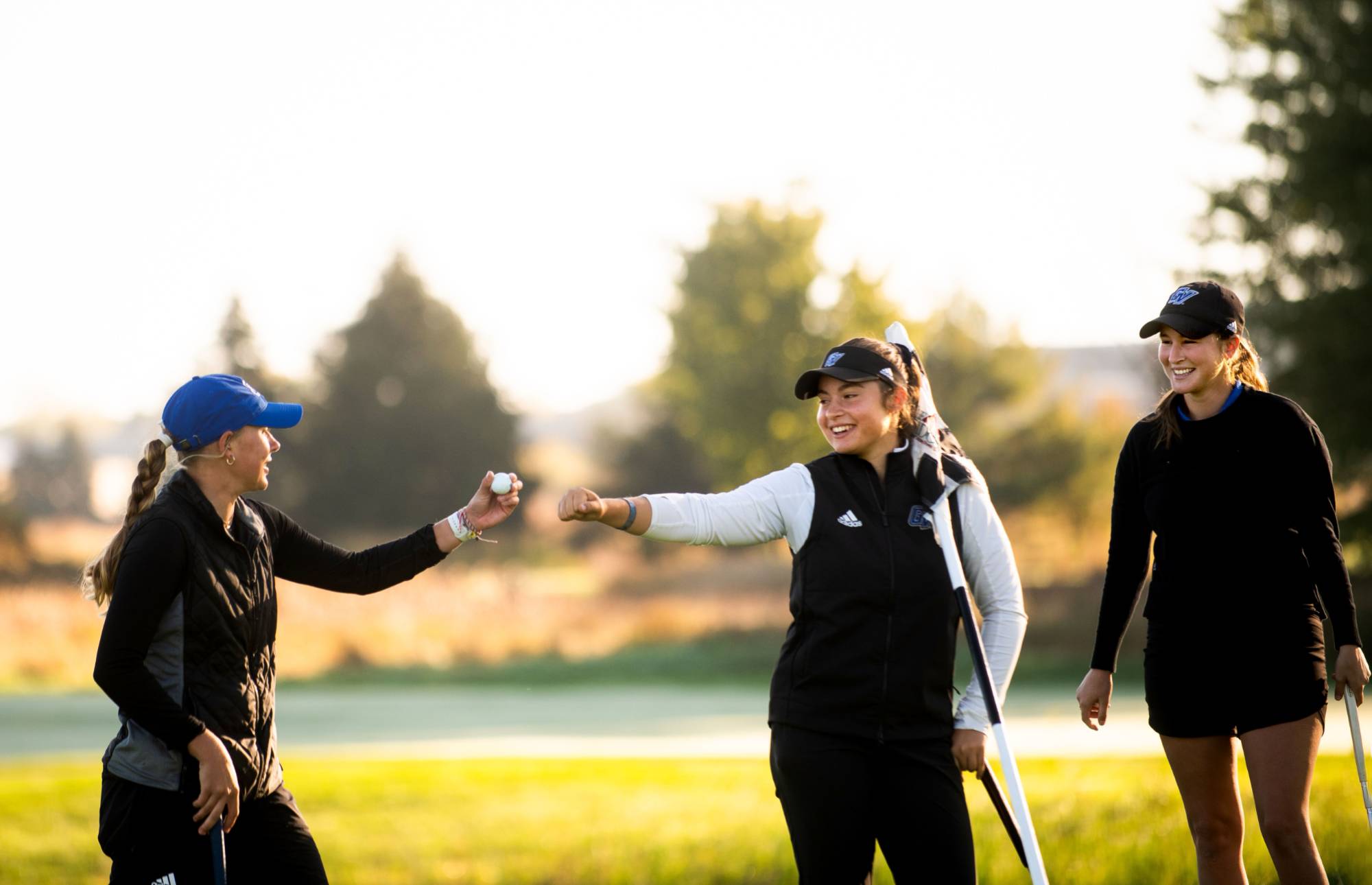 three female golfers all on the GVSU team celebrating a nice shot on the course